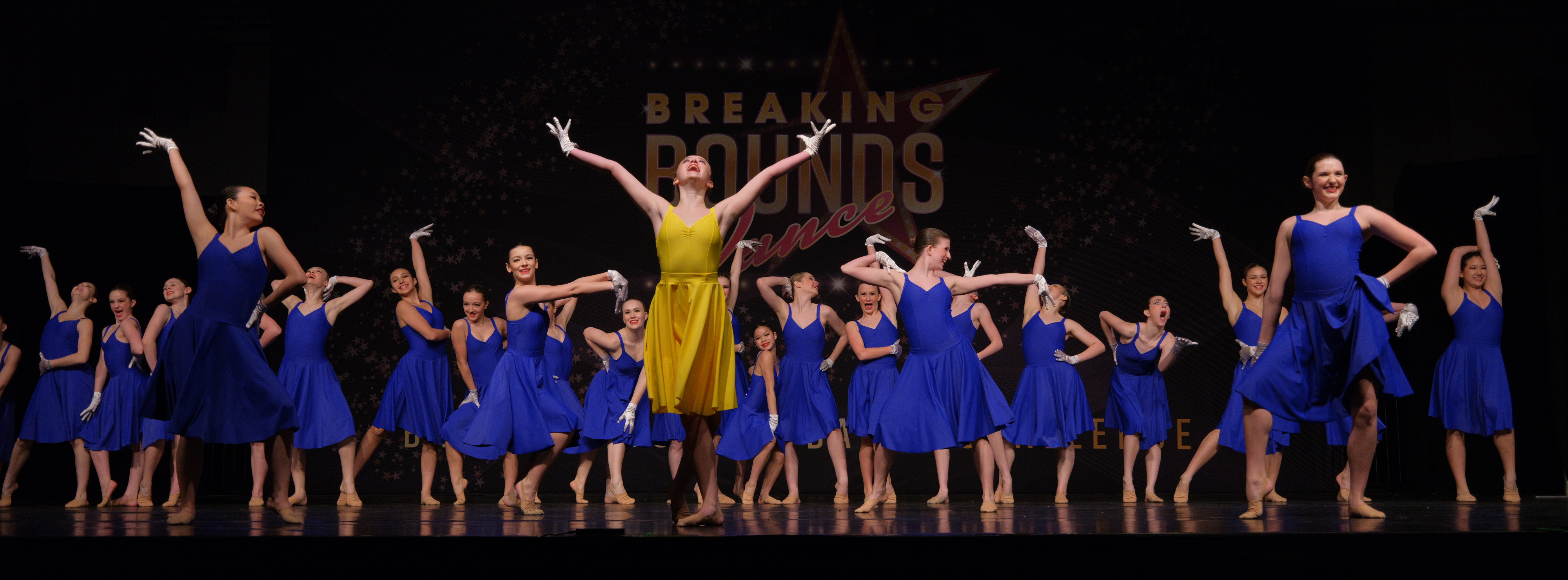 Full-stage group number, soloist in yellow, Breaking Bounds Dance Challenge
